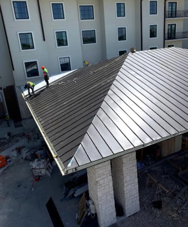 Crew installing standing seam metal roof panels on a commercial project in Ambler